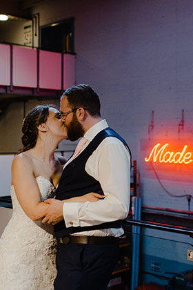 couple pose in front of wedding sign